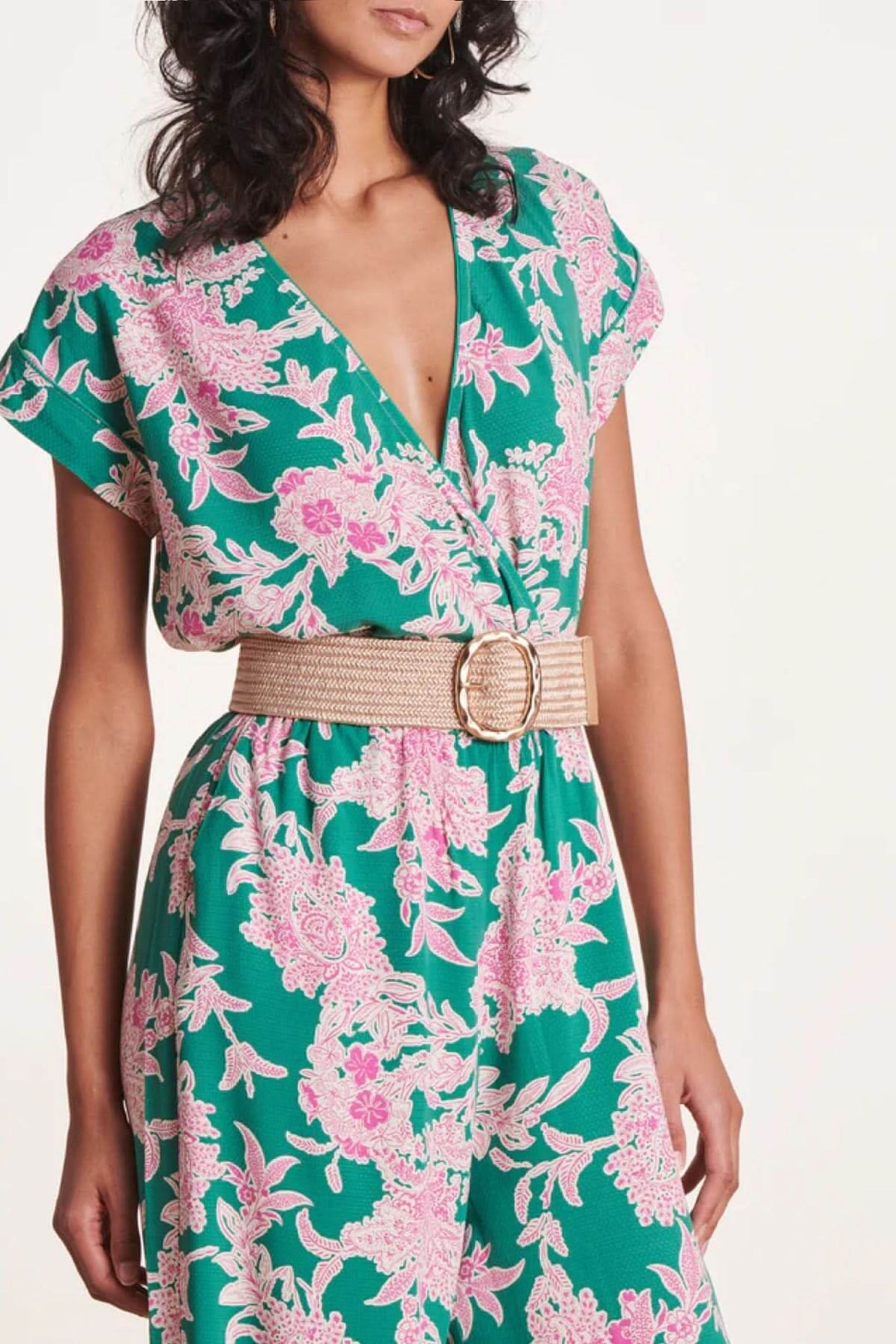 Femme portant une ceinture large élastique avec boucle dorée sur une robe à fleurs colorées.