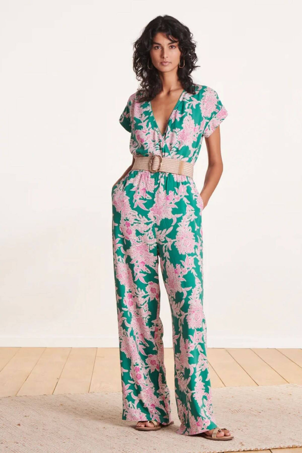 Modèle féminin portant une combinaison florale verte avec ceinture large élastique en beige.