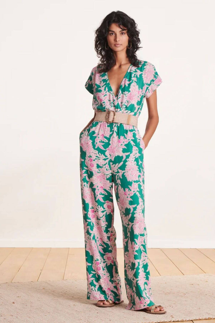 Modèle féminin portant une combinaison florale verte avec ceinture large élastique en beige.