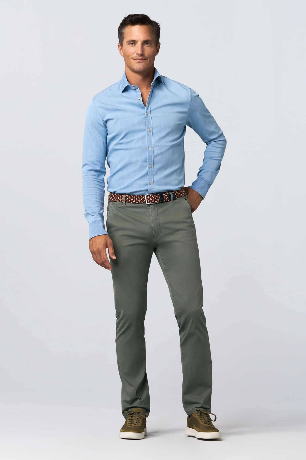 Homme portant une chemise bleue, pantalon gris et ceinture tressée multicolore, style décontracté.