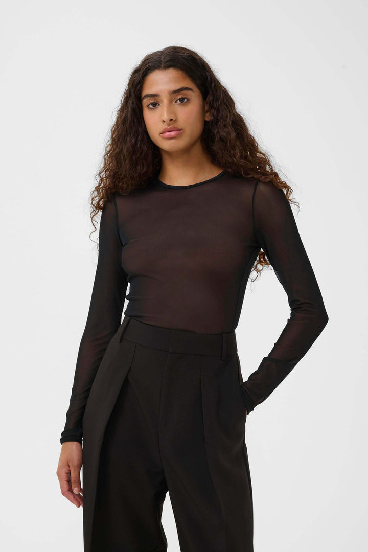 Femme portant le Chandail Kaia en tulle transparent à manches longues, coupe ajustée élégante et moderne, fond blanc, mode contemporaine.