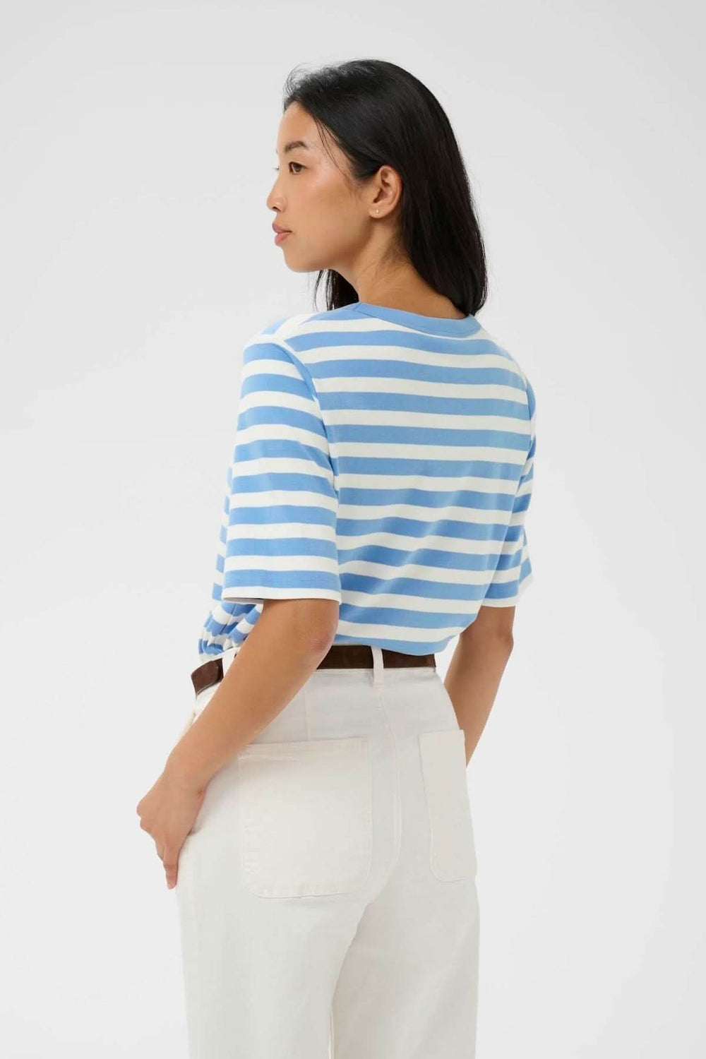 Chandail Ratana ligné à rayures bleues pour un look décontracté, porté avec pantalon blanc.