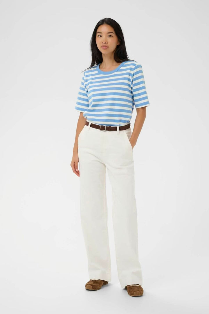 Femme portant un Chandail Ratana ligné à rayures bleues et blanches, coupe droite et encolure arrondie, look décontracté.
