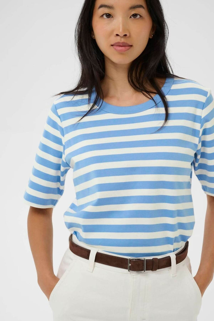 Femme portant le Chandail Ratana ligné à rayures bleues et blanches avec manches courtes, style décontracté et encolure arrondie.