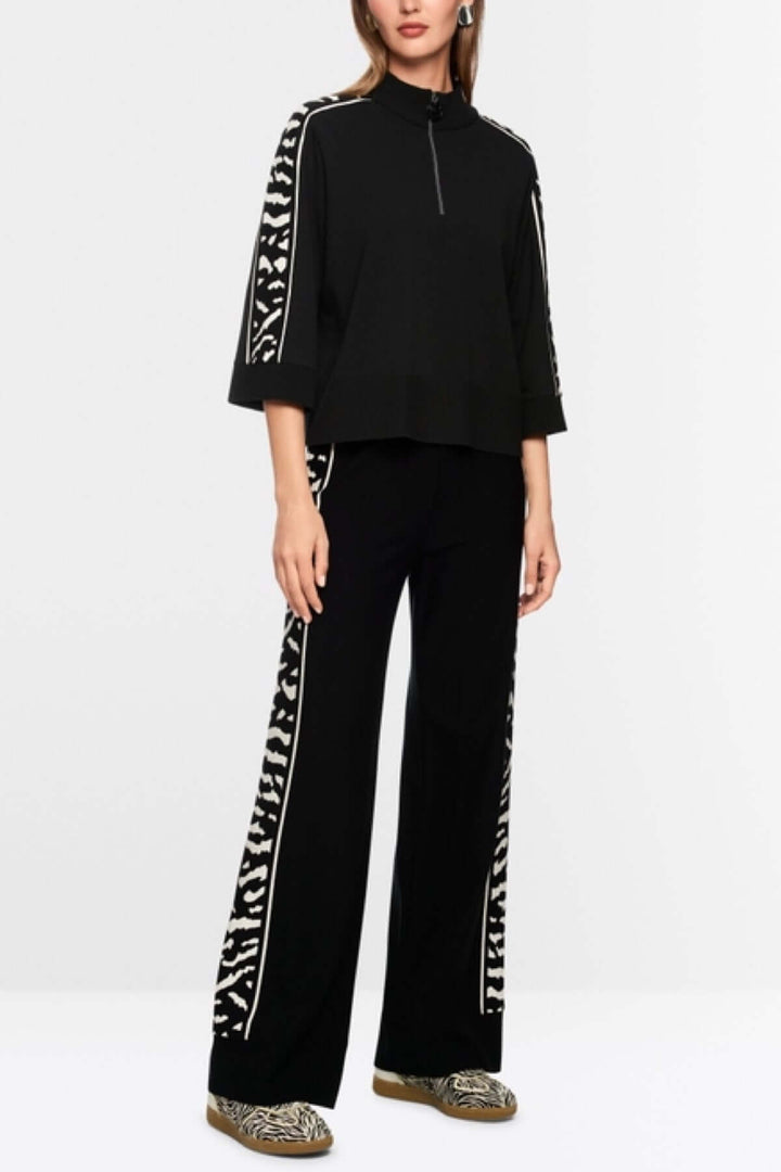 Chandail ample noir avec manches 3/4 et bande motif animalier, fermeture éclair au col, fabriqué de manière responsable.