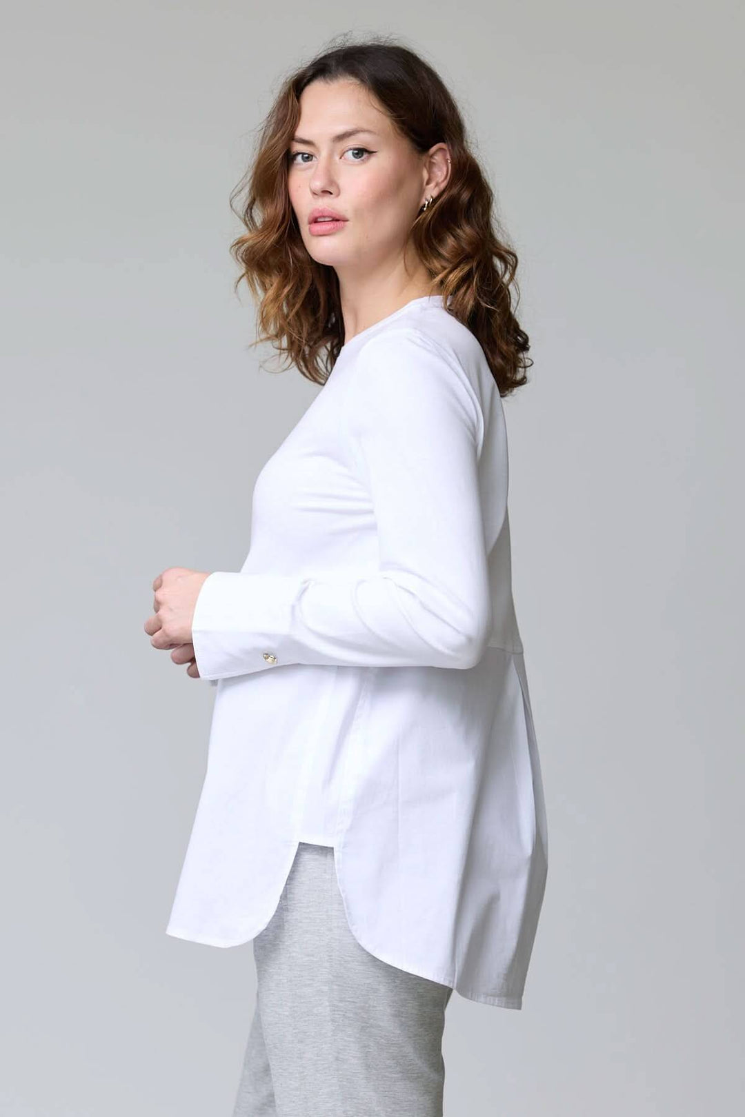 Femme portant un chandail à boutons décoratifs blanc avec manches longues, style chic décontracté.