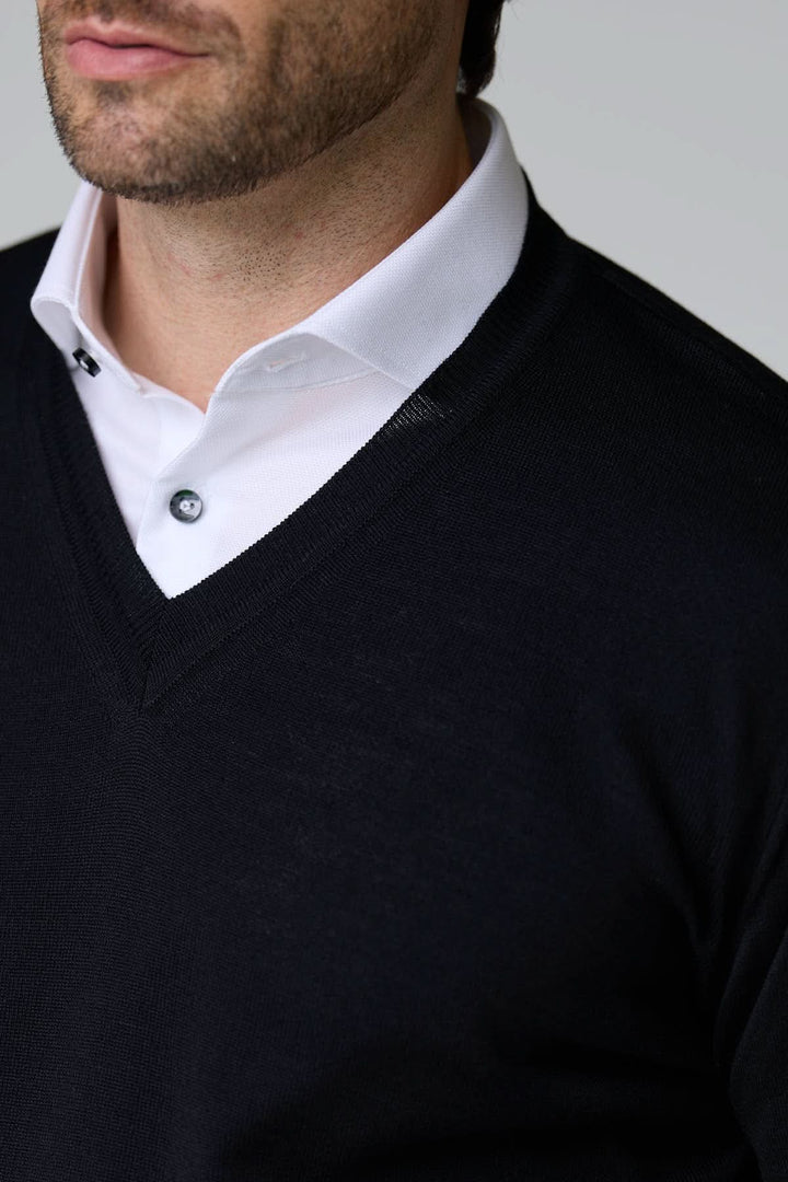 Chandail col en V en laine mérinos noir sur chemise blanche, pour un style élégant et intemporel. Décris moi le produit en français.