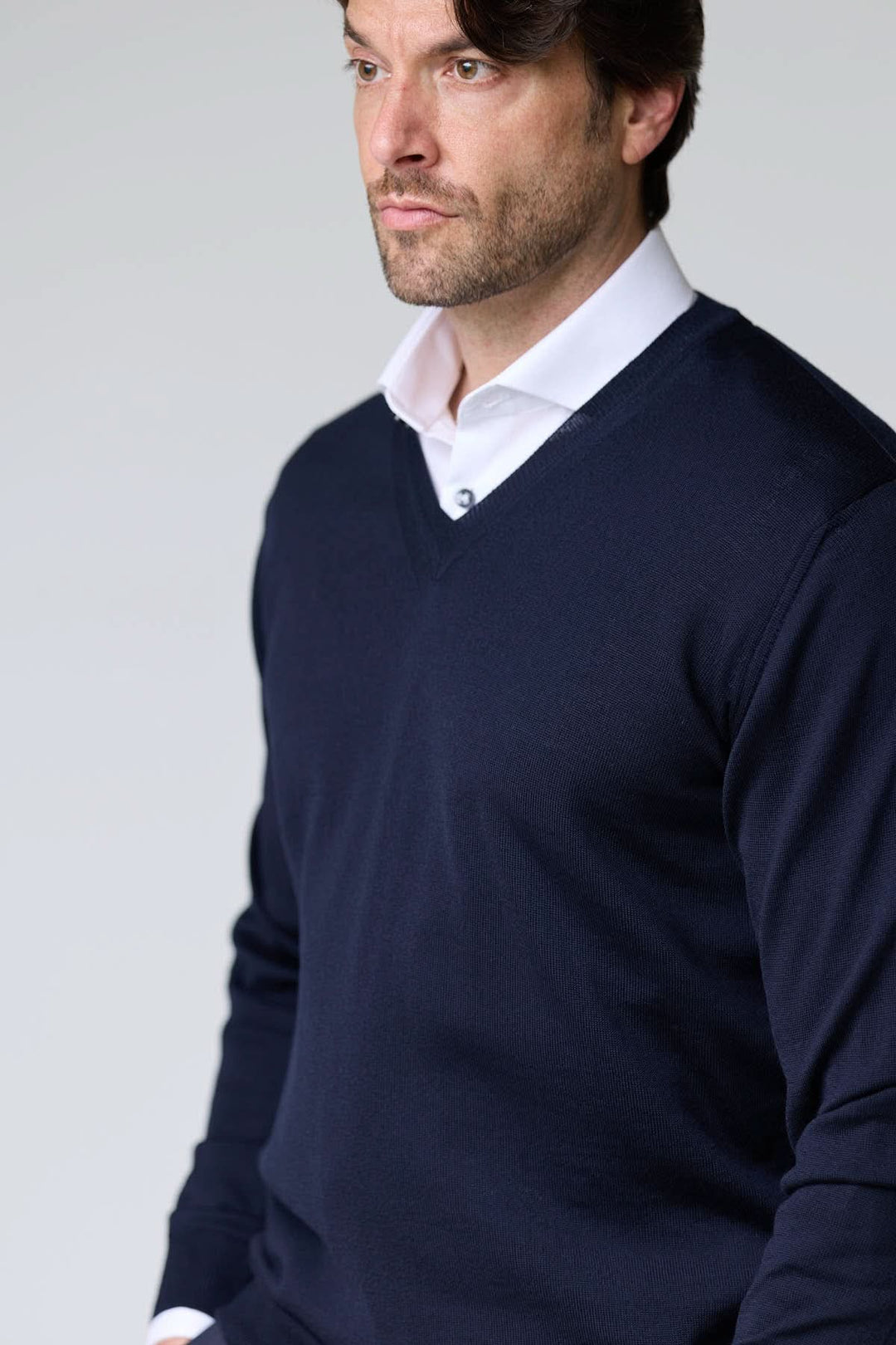 Homme portant un chandail col en V en laine mérinos bleu marine, élégant et intemporel.