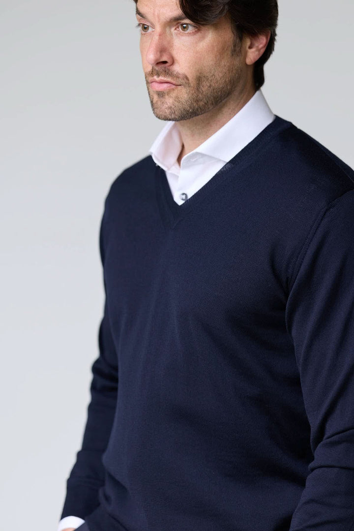 Homme portant un chandail col en V en laine mérinos bleu marine, élégant et intemporel.
