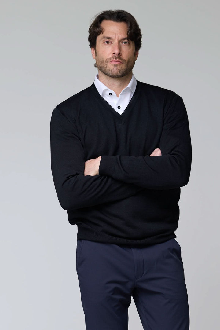 Homme portant un chandail col en V en laine mérinos noir, élégant et intemporel.