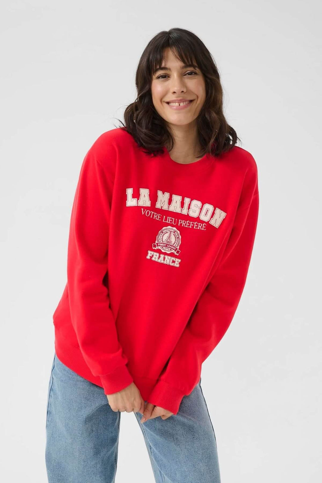Chandail à col rond rouge avec inscription brodée, style universitaire décontracté, tenue confortable.