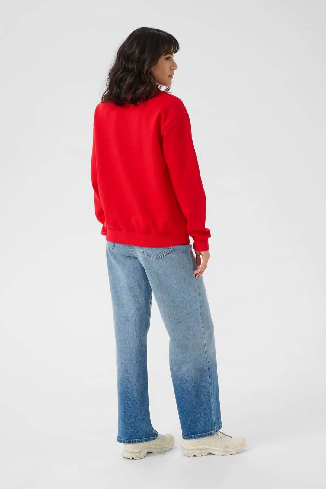 Femme portant un chandail à col rond rouge avec jeans, style décontracté et rétro, coupe ample, vue arrière.