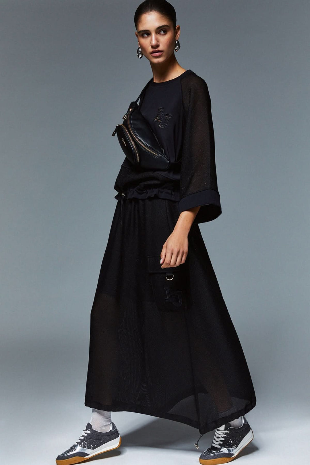 Femme portant un chandail court à manches larges avec une jupe longue, look décontracté et sophistiqué, style moderne.