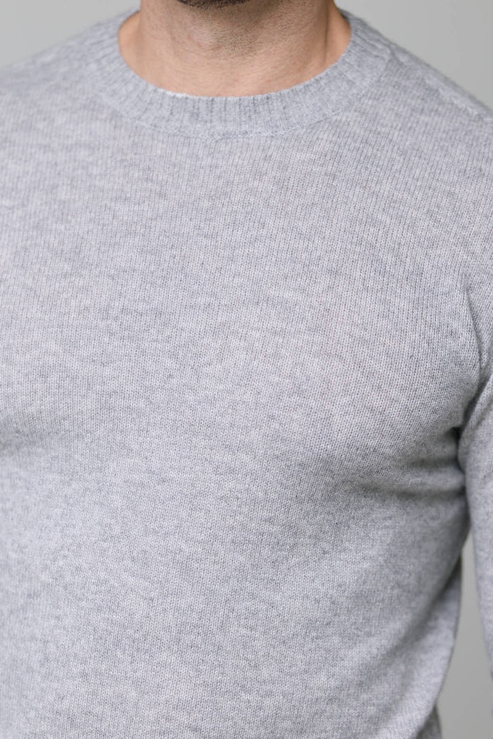 Chandail en laine gris avec encolure ronde, maille fine et douce, finition côtelée. Élégant et confortable, coupe ajustée, 100% laine.