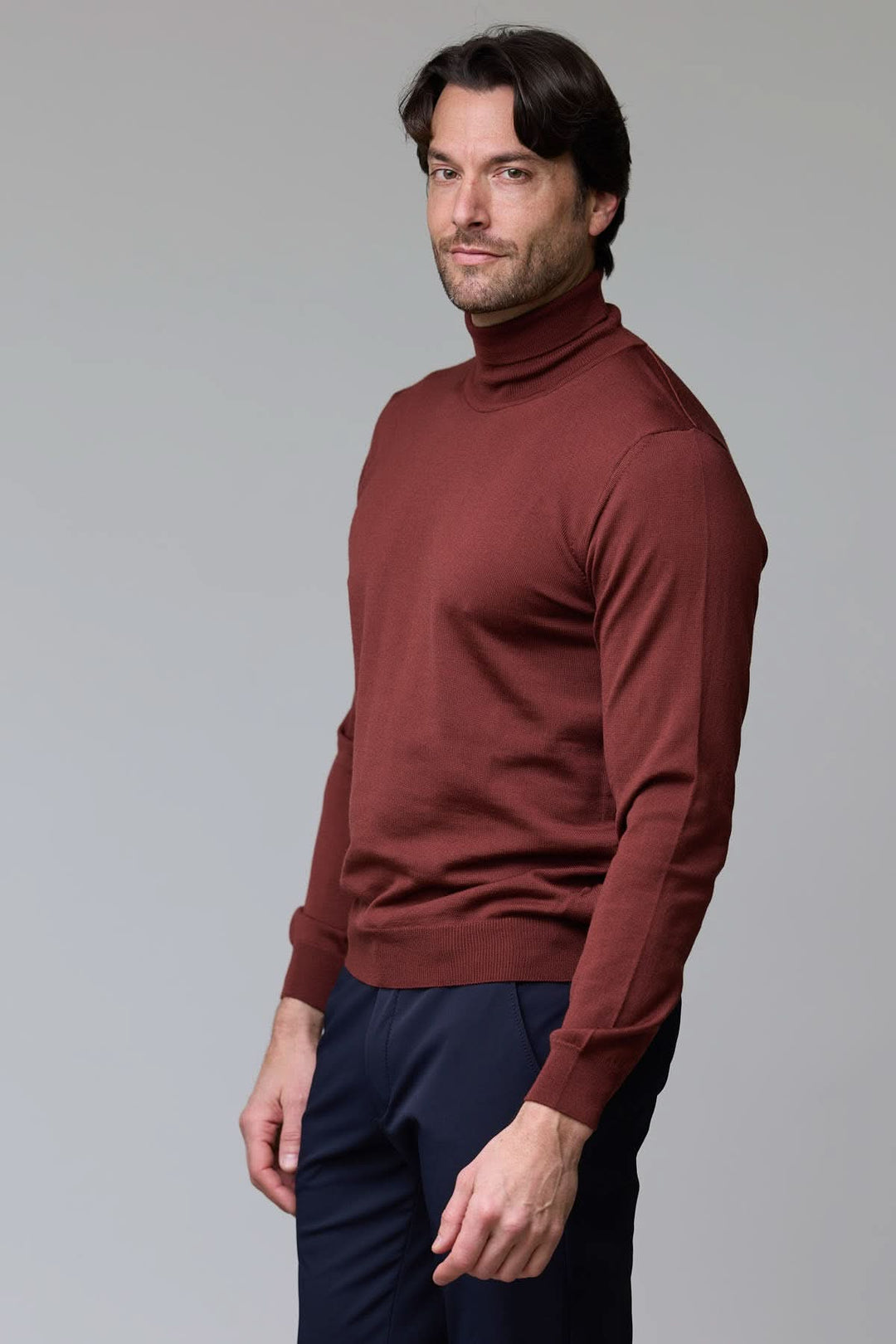 Homme portant un chandail à col roulé en laine mérinos rouge-brun, élégant et sophistiqué, parfait pour un style intemporel et confortable.