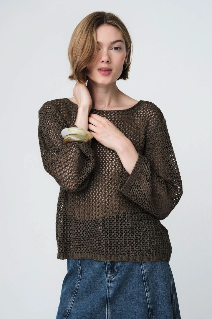 Femme portant un chandail en maille ajourée, manches longues, idéal pour superposer, style décontracté et moderne.
