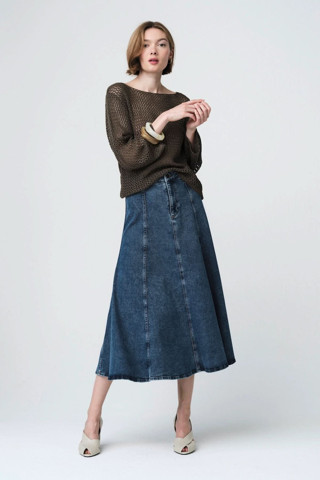 Chandail en maille ajourée porté avec une jupe en jean, idéal pour un style décontracté et élégant.