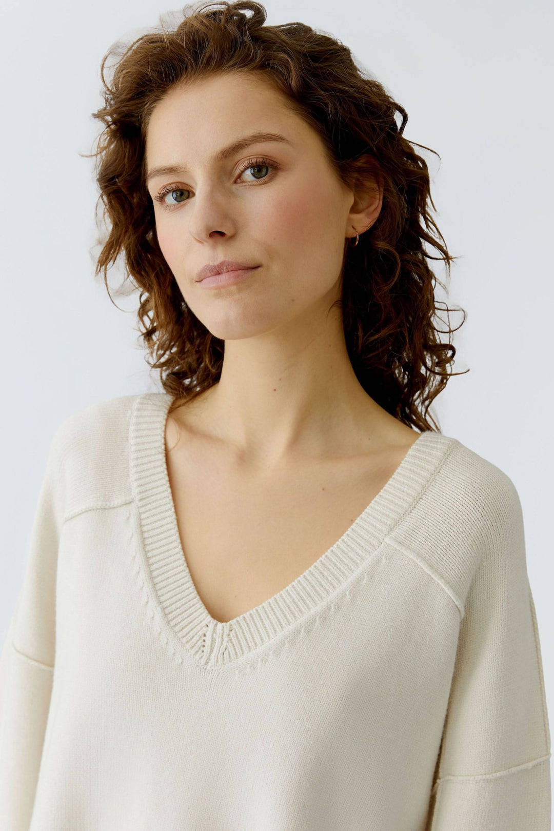 Femme portant un chandail en maille à col en V, style épuré avec encolure côtelée.