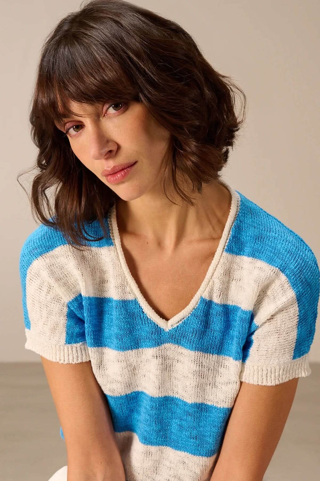 Femme portant un chandail en maille à col en V avec rayures bleues et blanches, parfait pour l&