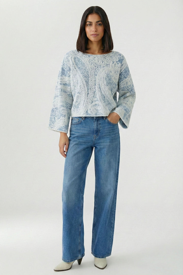 Chandail en maille imprimée à manches larges porté par une personne avec un jean, montrant le motif cachemire et les manches trois-quarts.