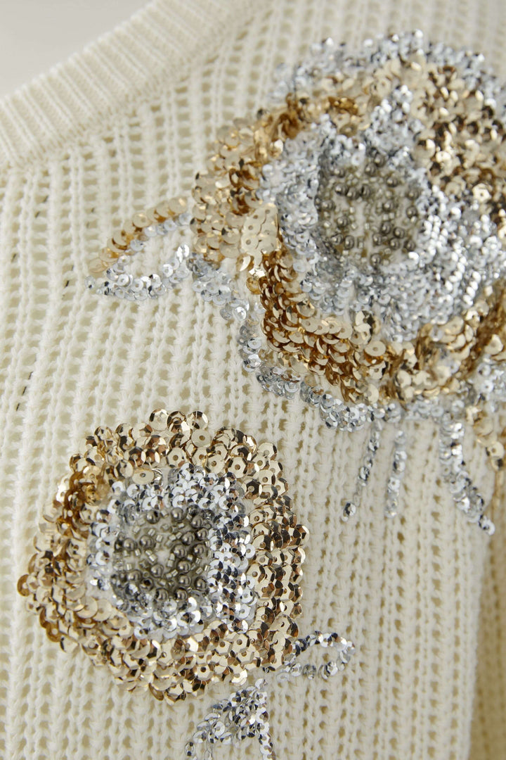 Chandail en maille texturée avec appliqués brodés décoratifs brillants. Décris moi le produit en français.