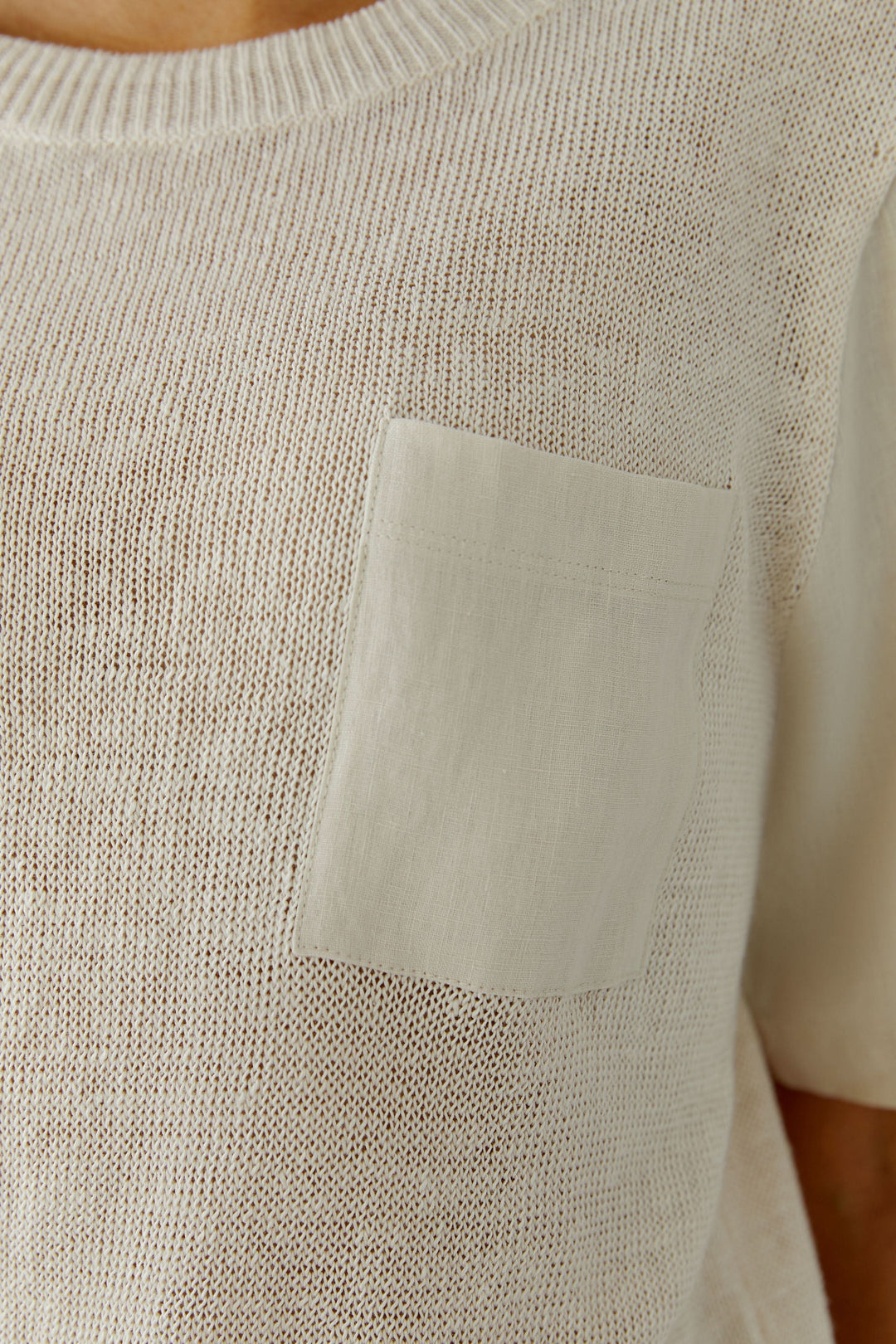 Chandail en maille texturée à manches courtes avec poche poitrine en tissu contrasté, parfait pour un style naturel et épuré.