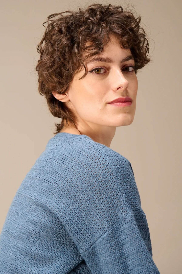 Femme portant un chandail en tricot texturé à manches longues bleu avec maille structurée et coupe moderne, vue de profil.