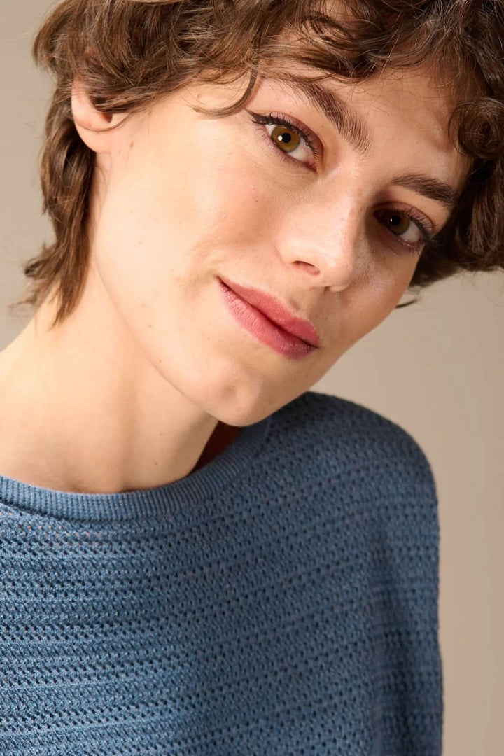 Femme portant un chandail en tricot texturé à manches longues bleu avec encolure ronde et maille structurée pour un look décontracté.