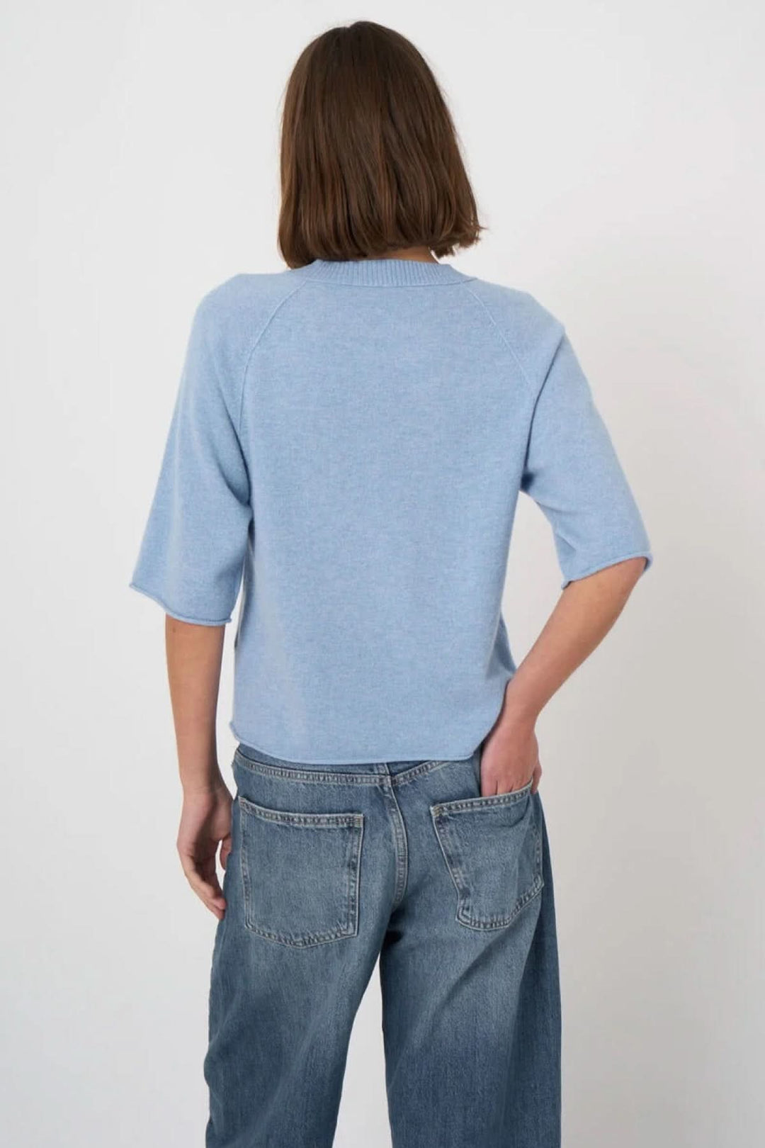 Personne portant un chandail à manches courtes bleu clair de retour, coupe droite et encolure ronde, style décontracté.