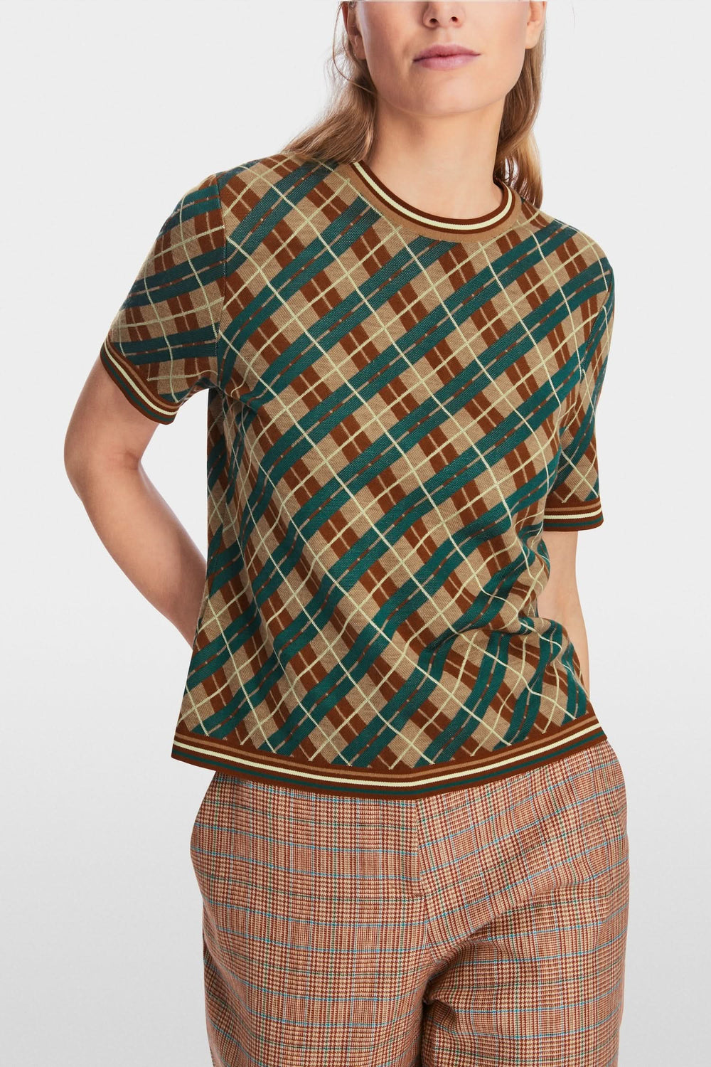 Chandail à motifs losanges en laine douce avec encolure ronde et manches courtes, porté avec un pantalon à carreaux.