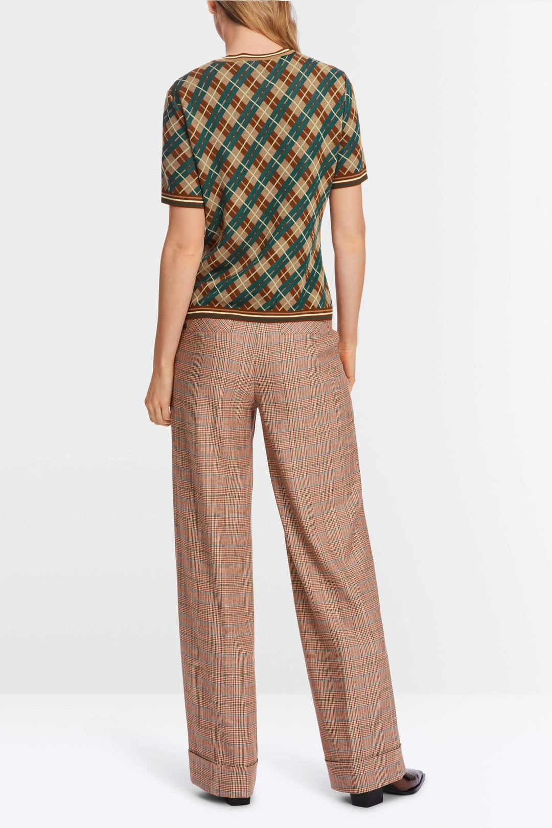 Pull à motifs losanges porté avec un pantalon à carreaux, vue de dos, style élégant pour un look décontracté.