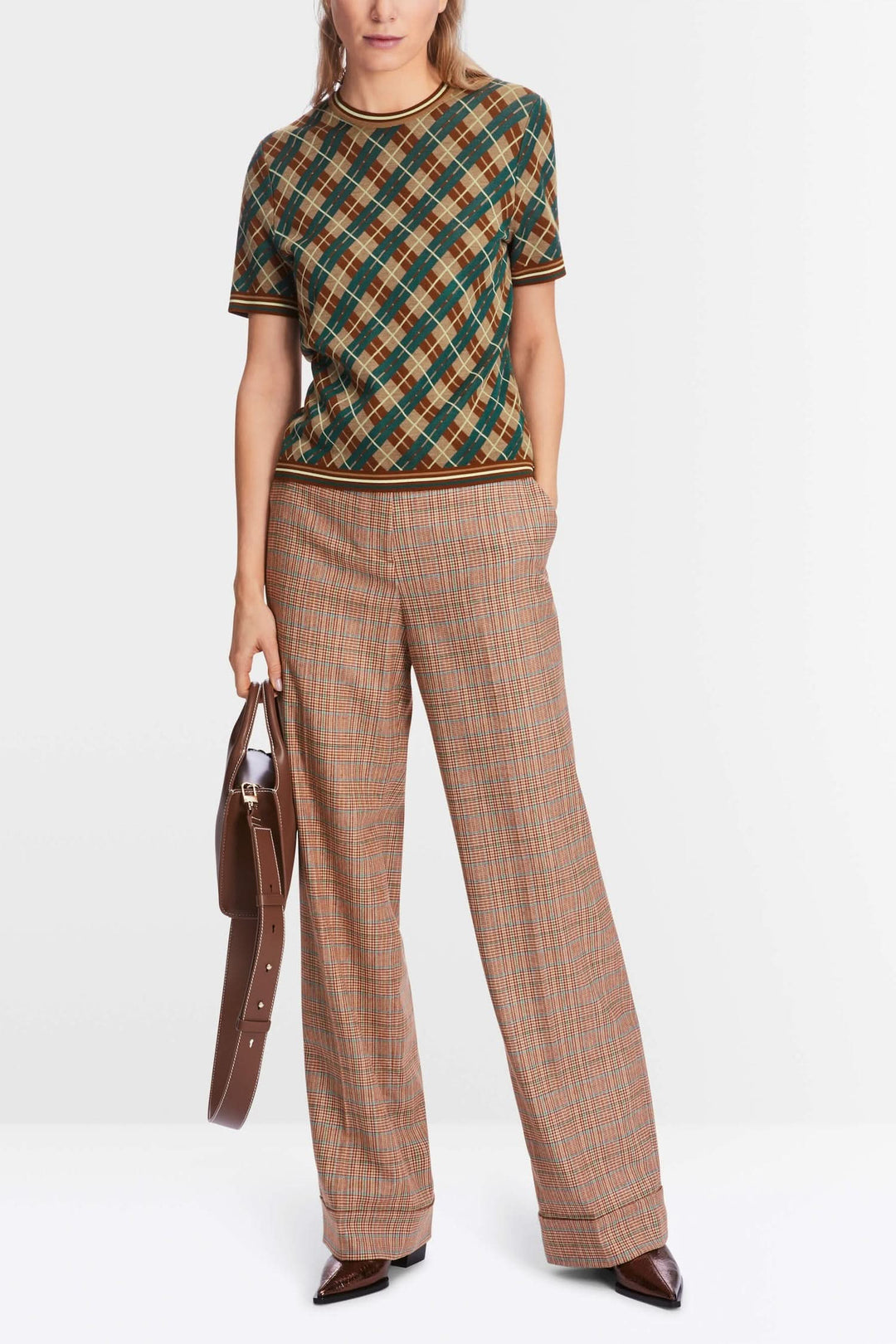 Chandail à motifs losanges avec bords côtelés, porté avec un pantalon à carreaux, style chic et décontracté.