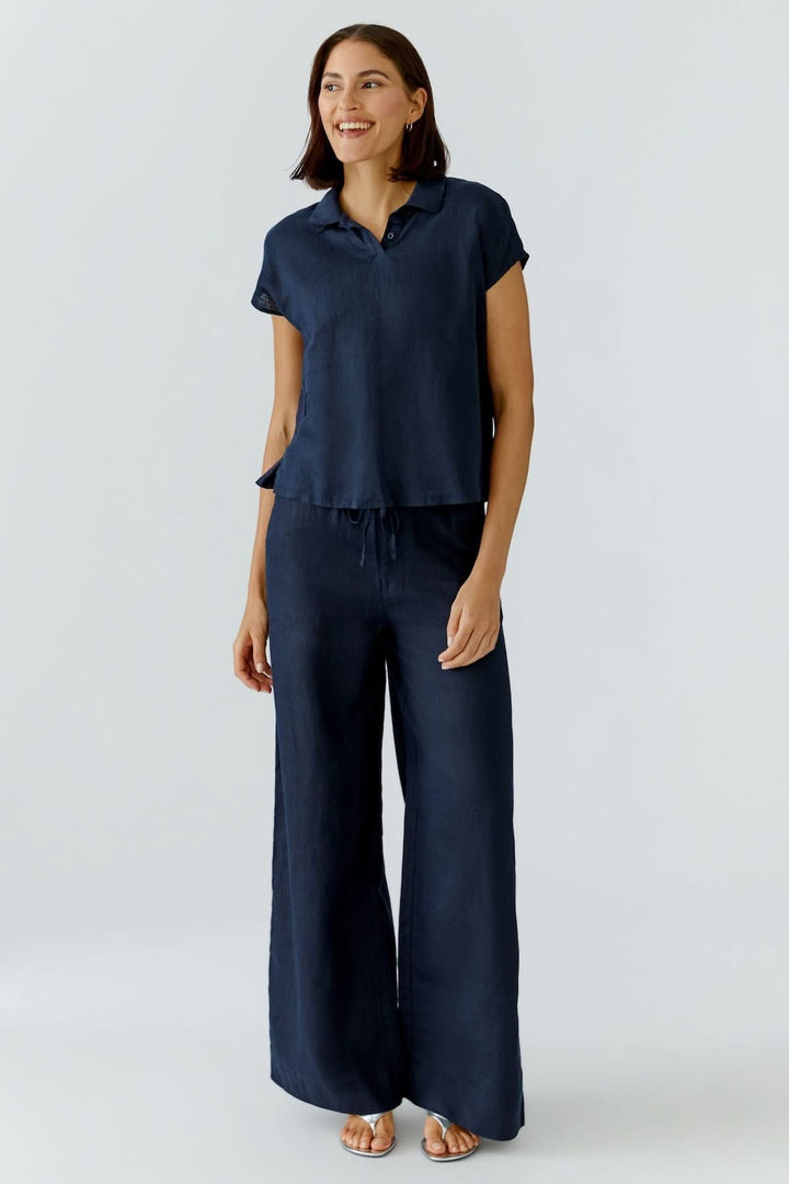 Femme portant un chandail polo fluide à manches courtes avec un pantalon ample, créant un look minimaliste et décontracté.