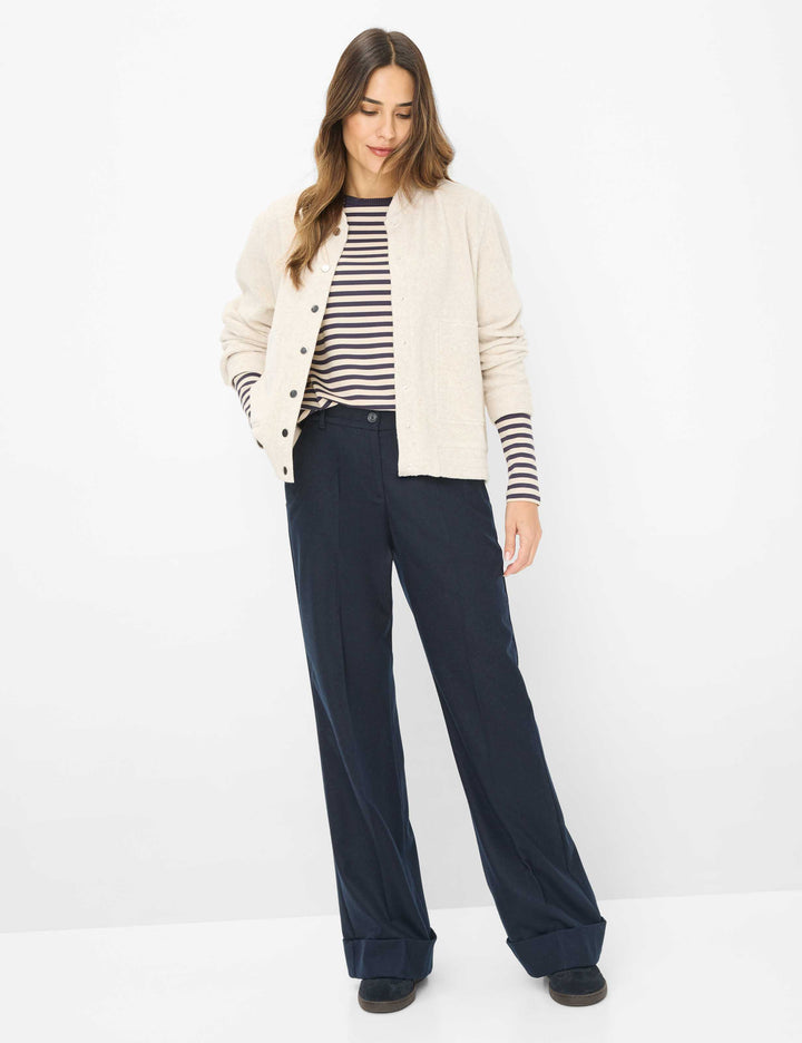 Femme portant un Chandail rayé CARINA L. avec une veste beige et un pantalon bleu marine, affichant une tenue chic et décontractée.