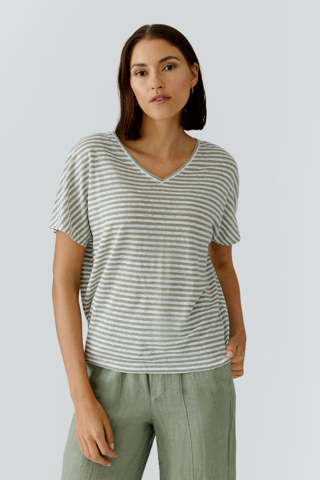 Femme portant un chandail à rayures col en v avec coupe décontractée et manches courtes, parfait pour un look moderne et quotidien.