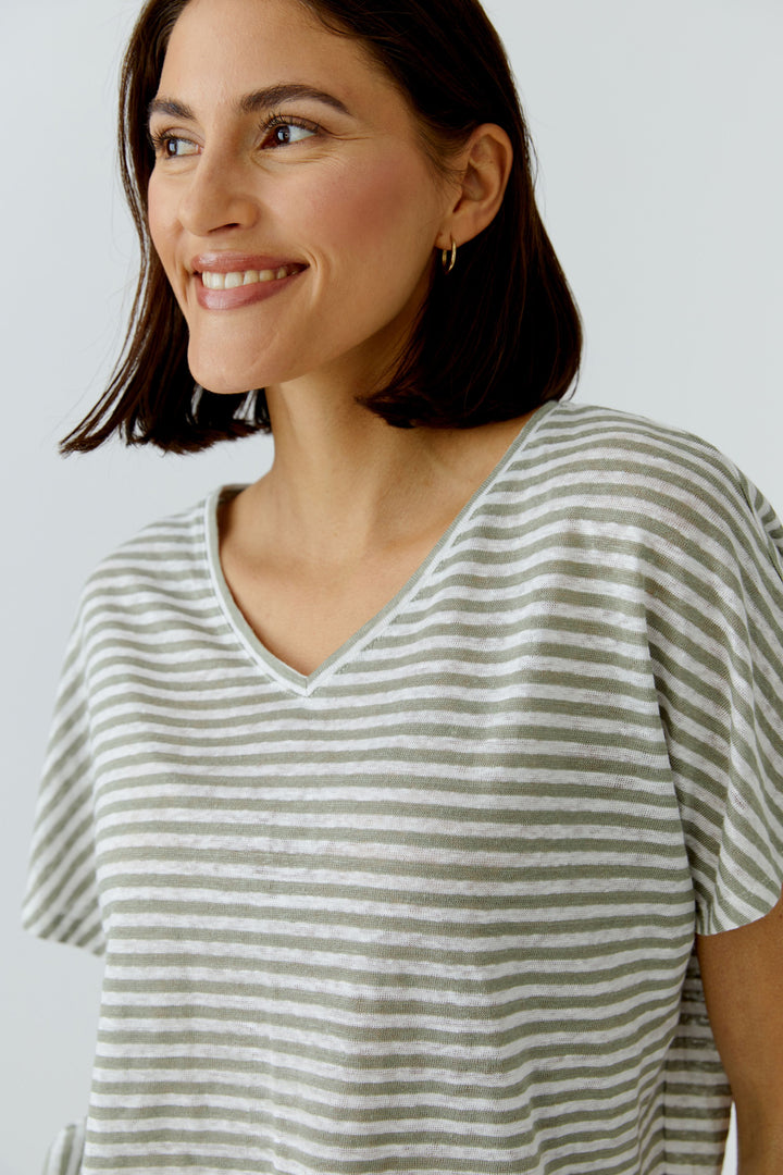 Femme portant un chandail à rayures col en v décontracté avec manches courtes, parfait pour le quotidien et le confort.
