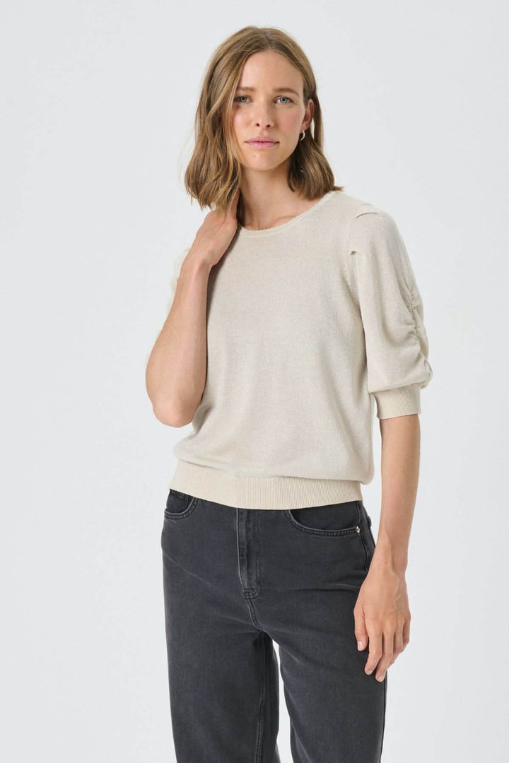 Femme portant le Chandail scintillant Varaia avec manches courtes et encolure ronde, style élégant et confortable.