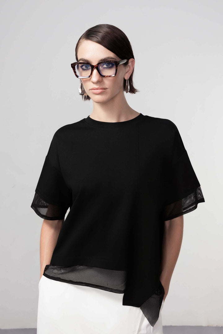 Femme portant un chandail texturé noir avec manches transparentes, style moderne et détails graphiques, chandail texturé tendance.