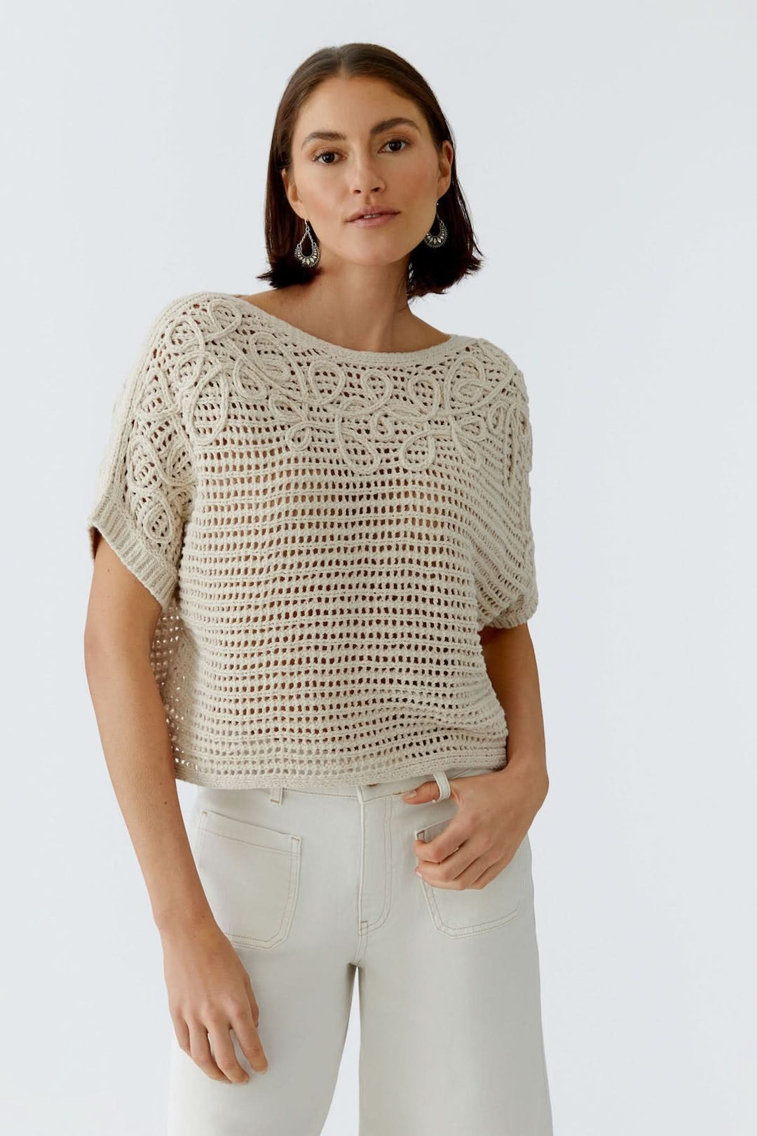 Femme portant un chandail tricot ajouré texturé beige élégant avec encolure dégagée. Décris moi le produit en français.