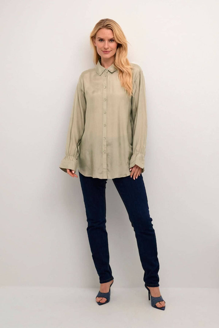 Chemise Arina en tissu léger, coupe décontractée, manches longues, style intemporel, portée avec jeans.