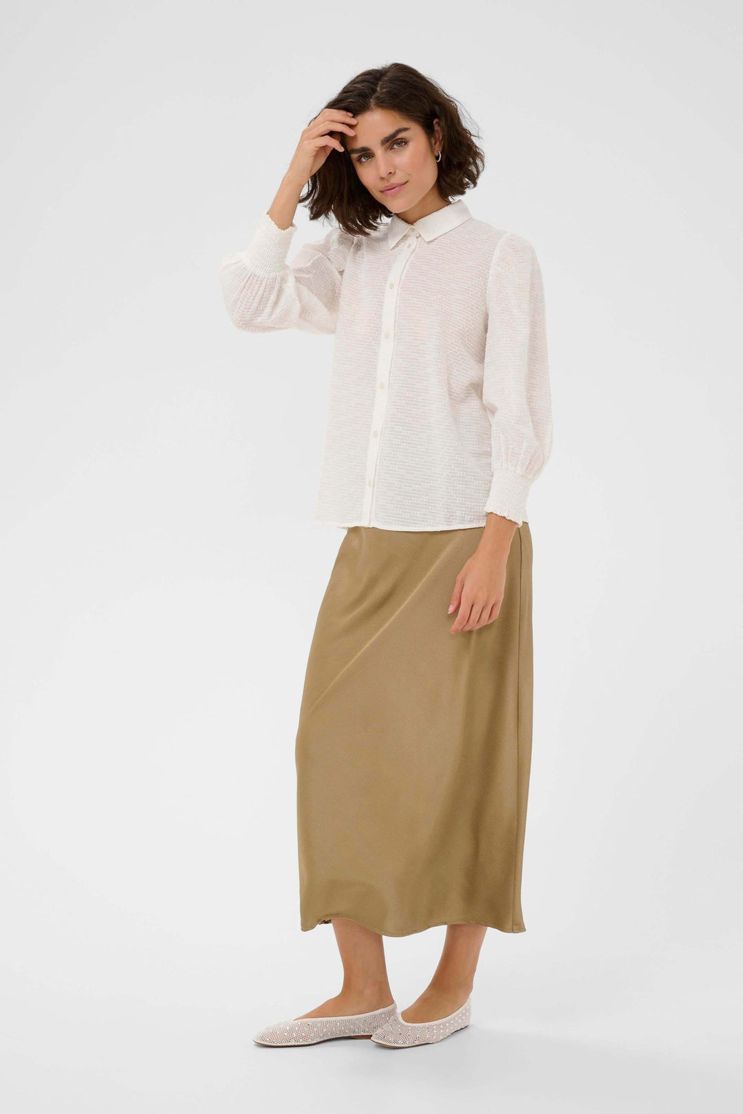 Femme portant la Chemise Penelope texturée à manches bouffantes, élégante et moderne, avec une jupe longue beige.