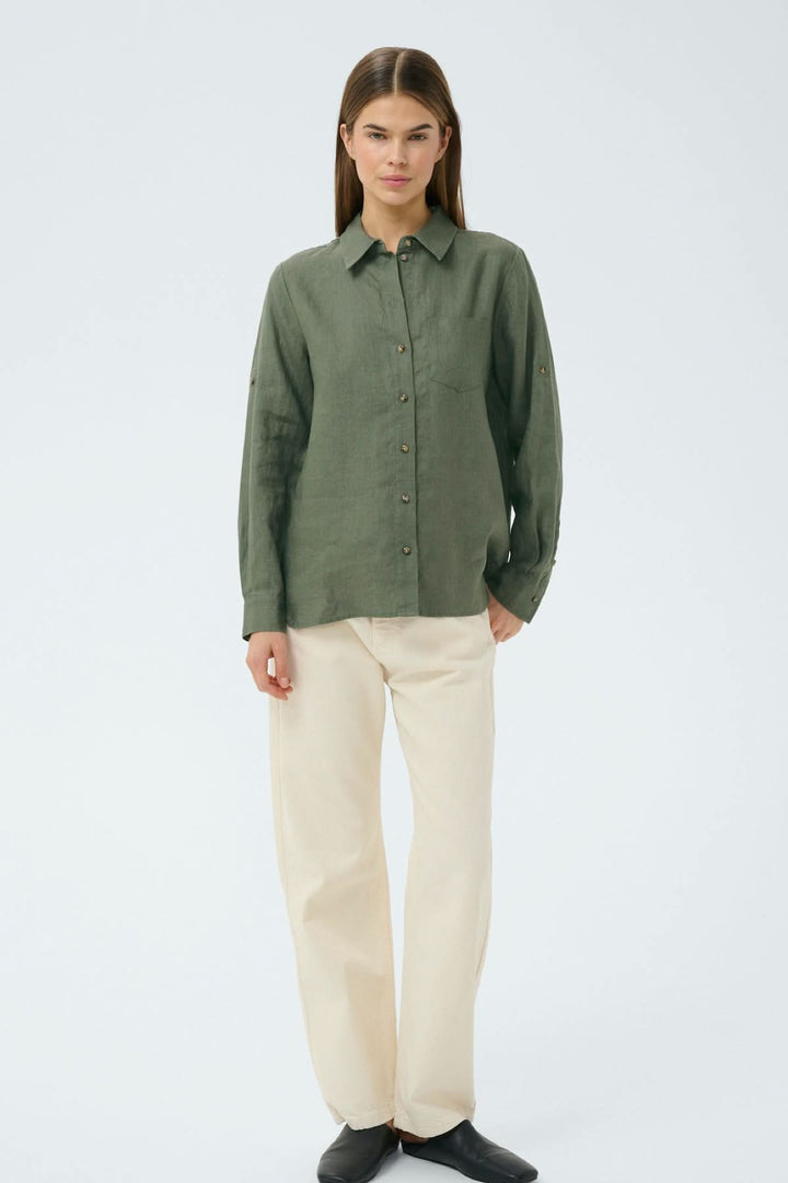 Femme portant une chemise en lin Dilana verte, idéale pour un look décontracté et raffiné.