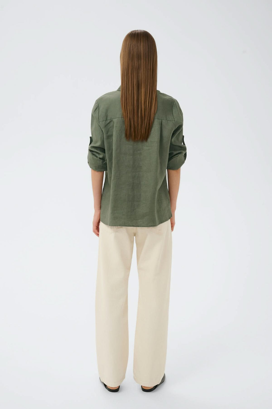 Vue arrière de la chemise en lin Dilana, manches longues retroussées, couleur kaki, coupe ample et décontractée, portée avec un pantalon clair.