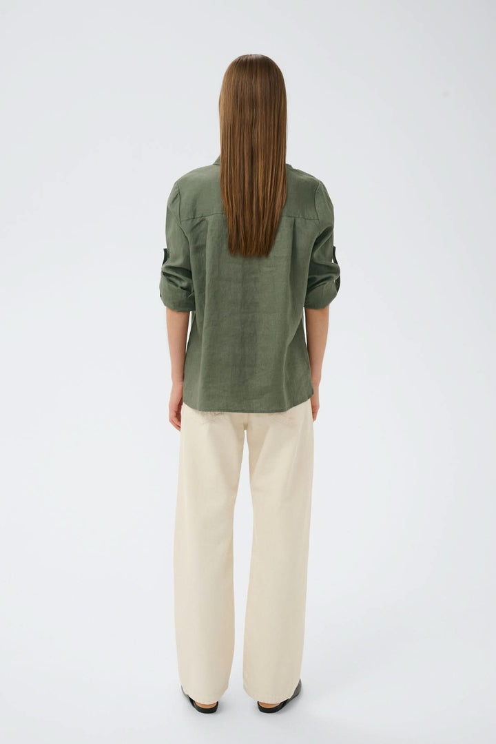 Vue arrière de la chemise en lin Dilana, manches longues retroussées, couleur kaki, coupe ample et décontractée, portée avec un pantalon clair.