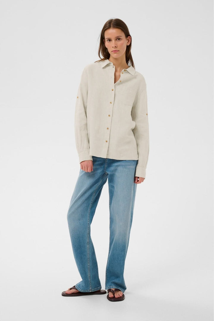Femme portant une chemise en lin Dilana légère et décontractée avec jeans, parfait pour un style raffiné et polyvalent.