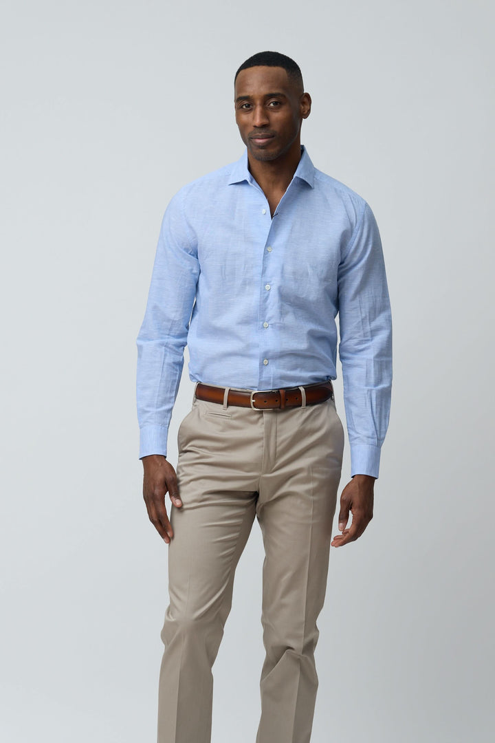 Homme portant une chemise en lin légère et raffinée, bleu clair, avec une coupe ajustée, manches longues et col structuré, style élégant.