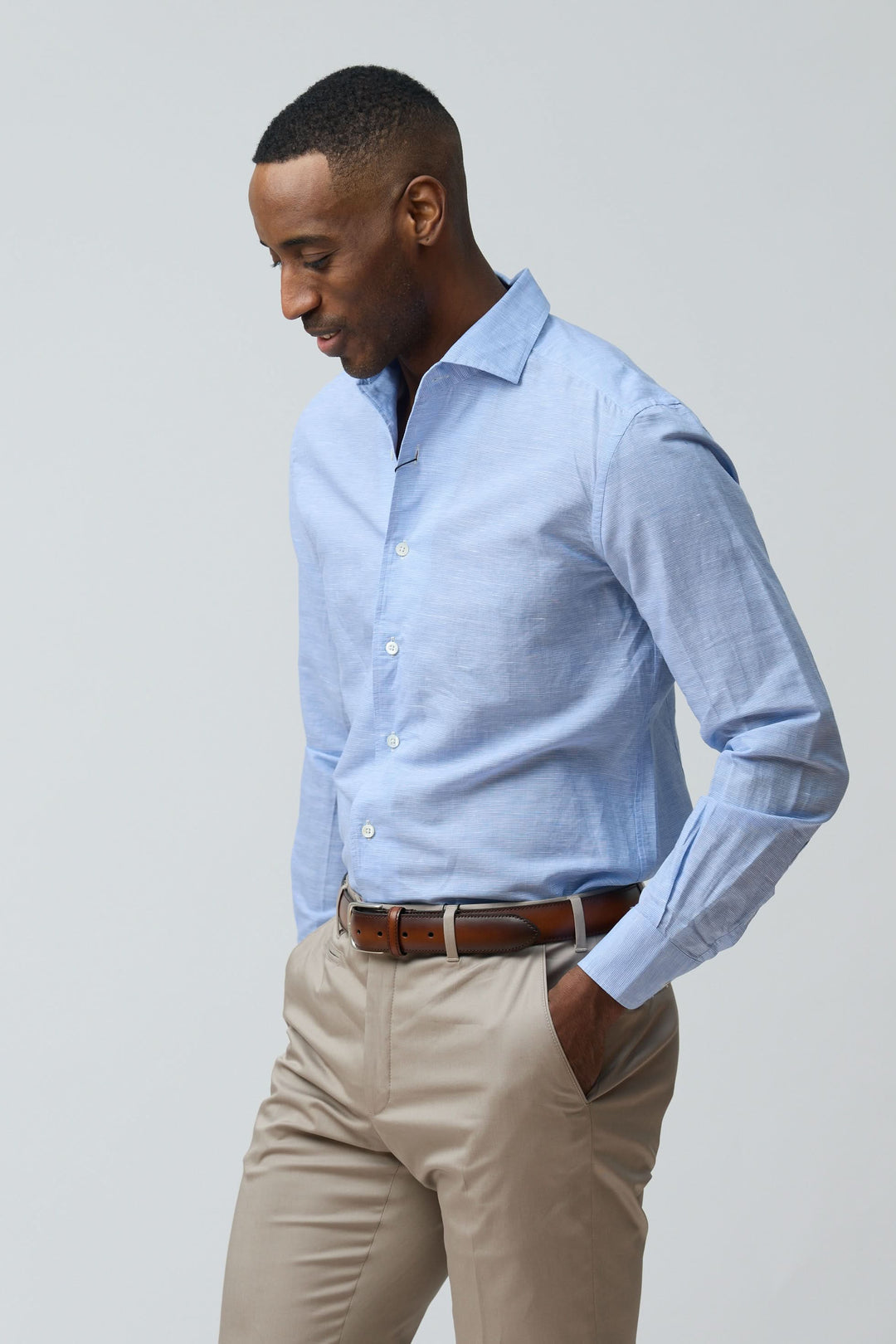 Homme portant une chemise en lin légère et raffinée, coupe ajustée, bleu clair, avec manches longues et col classique structuré.