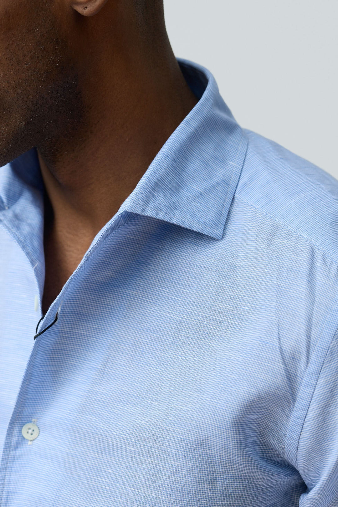 Homme portant une chemise en lin légère et raffinée, tissu bleu clair avec col structuré et fermeture boutonnée.