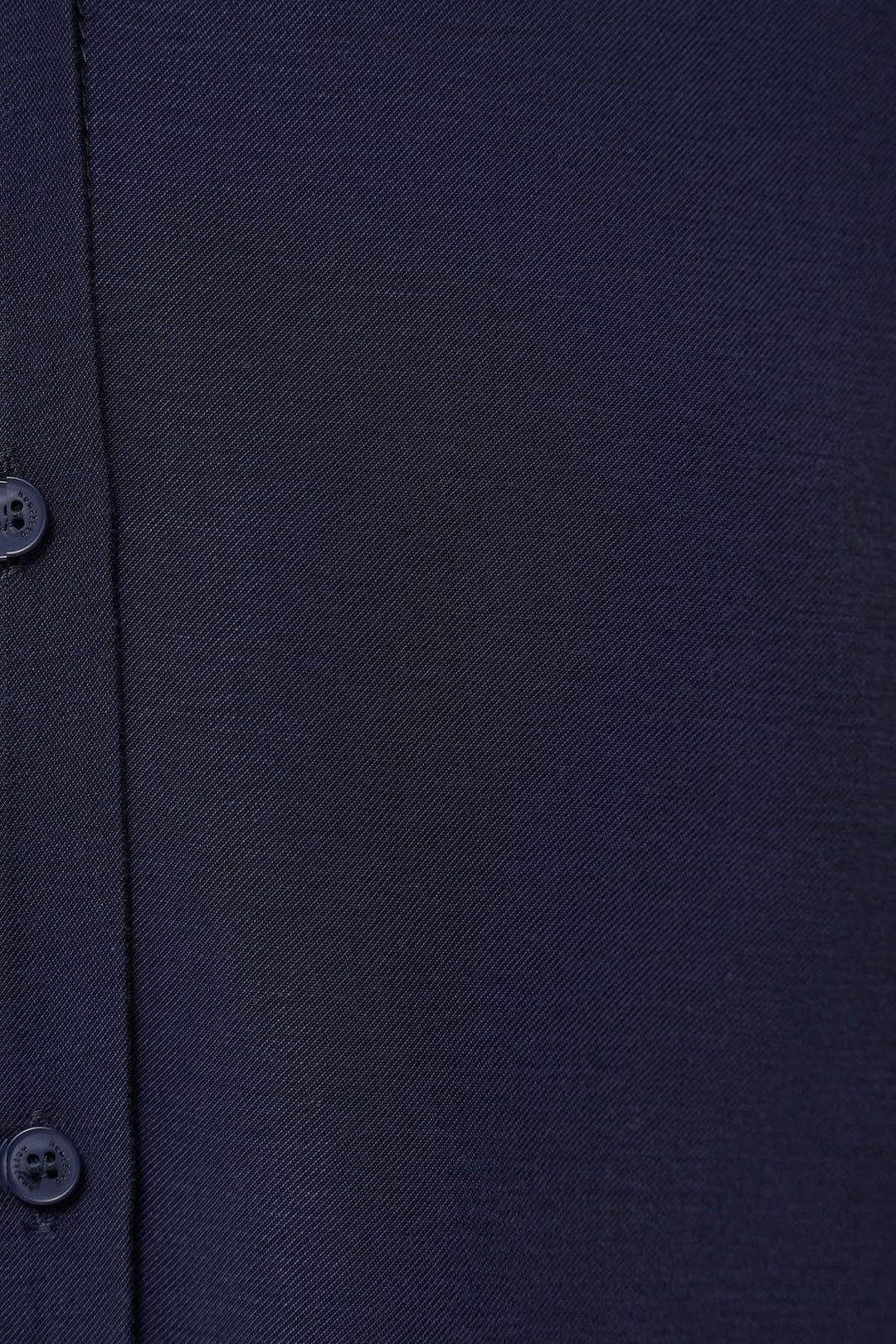 Détail d'une chemise fluide en tissu navy, avec boutons et texture élégante, alliant confort et style.