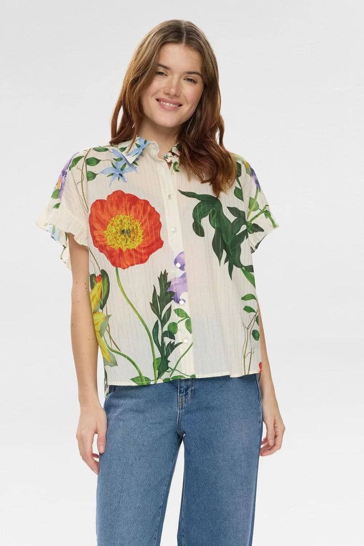Chemise fluide imprimée à manches volantées avec fleurs colorées, col classique, manches courtes et coupe droite légèrement ample.